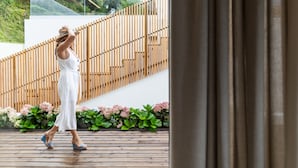 A person walking on a wooden deck with a modern staircase and greenery in the background. - Quinta da Abelheira (Ponta Delgada)