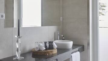 Een moderne badkamer met een grote spiegel, een witte wastafel en een glazen kandelaar.