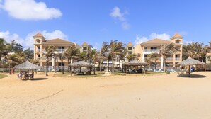 A beachfront hotel with multiple buildings, palm trees, and beach umbrellas. - Atlantic Palace Apart-Hotel (Aquiraz)