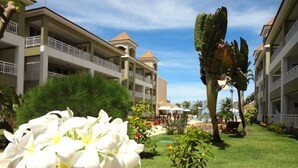 A hotel courtyard with a large white flower, palm trees, and a pool area. - Atlantic Palace Apart-Hotel (Aquiraz)