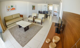 Una sala de estar con sofá, mesa de centro y sillas, un comedor con mesa y sillas, y un dormitorio con cama.