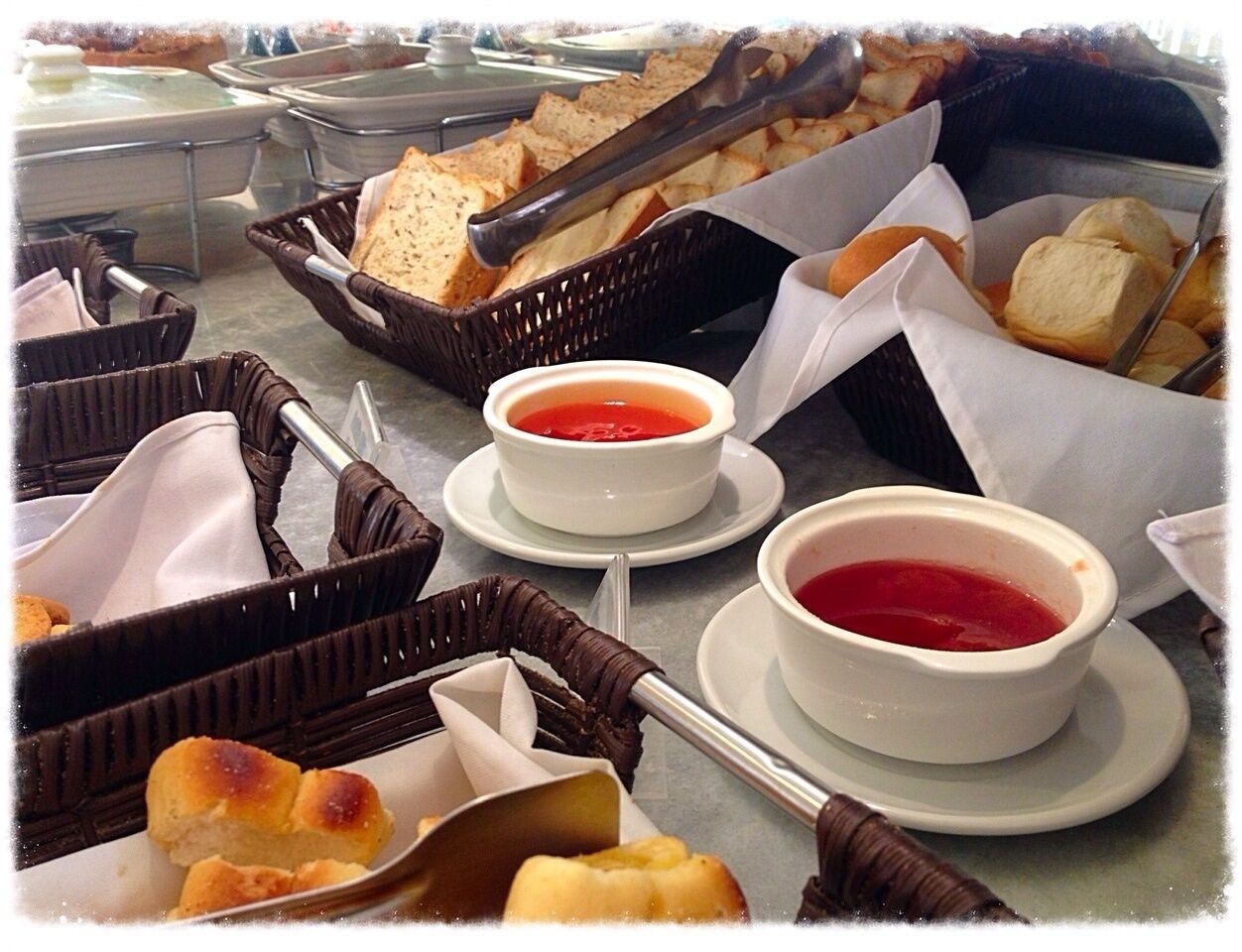 A buffet with various food items including bread, rolls, and bowls of soup.