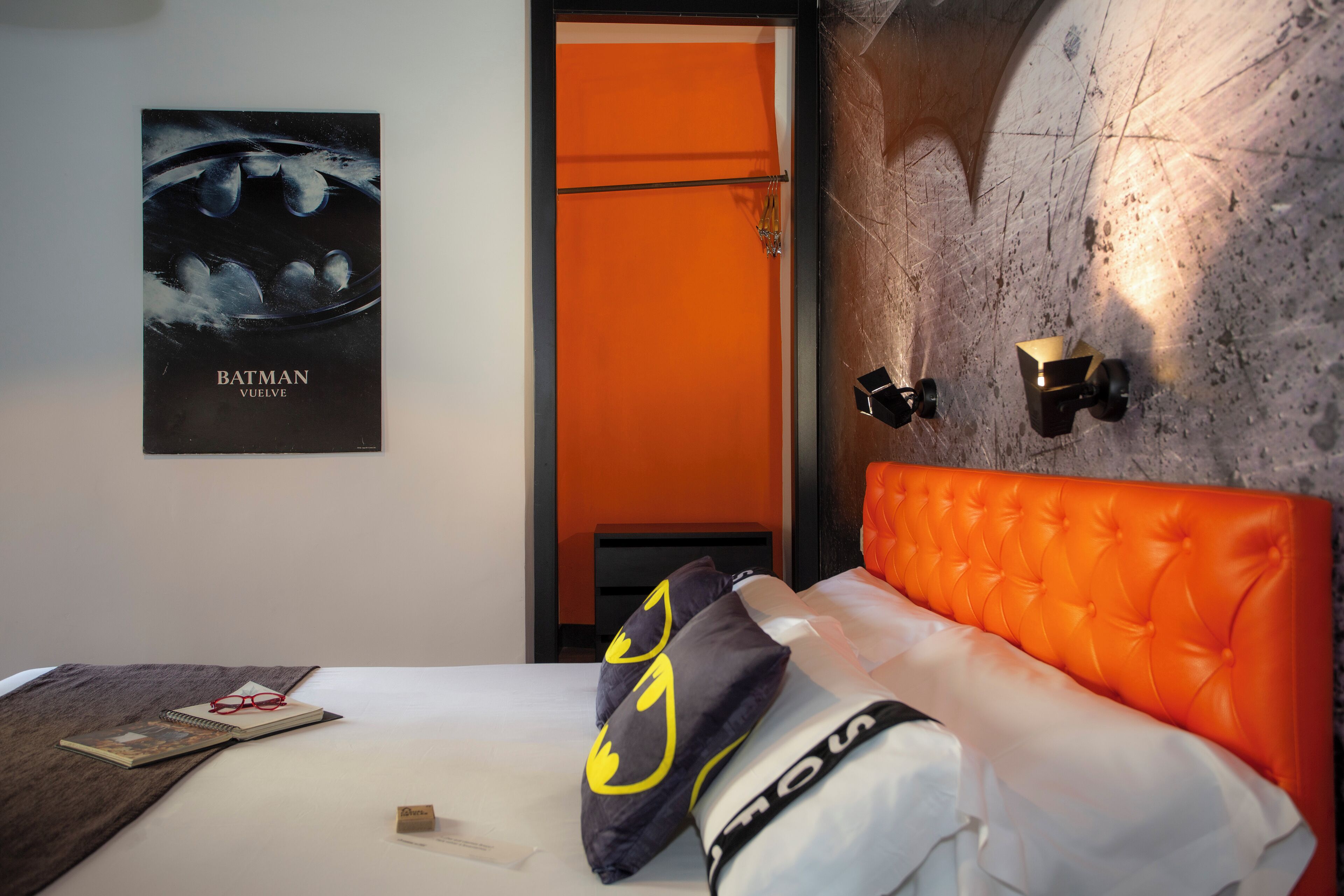 Una habitación de hotel con una cama, un cartel en la pared y una mesita de noche.