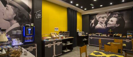 Restaurante com serviço de buffet, incluindo uma máquina de café e diversos tipos de comida.