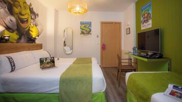 A hotel room with two beds, a television, a desk with a computer, and a mirror.