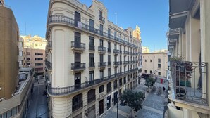 Un edificio de varios pisos con balcones, un primer piso de baldosas y un cielo despejado.