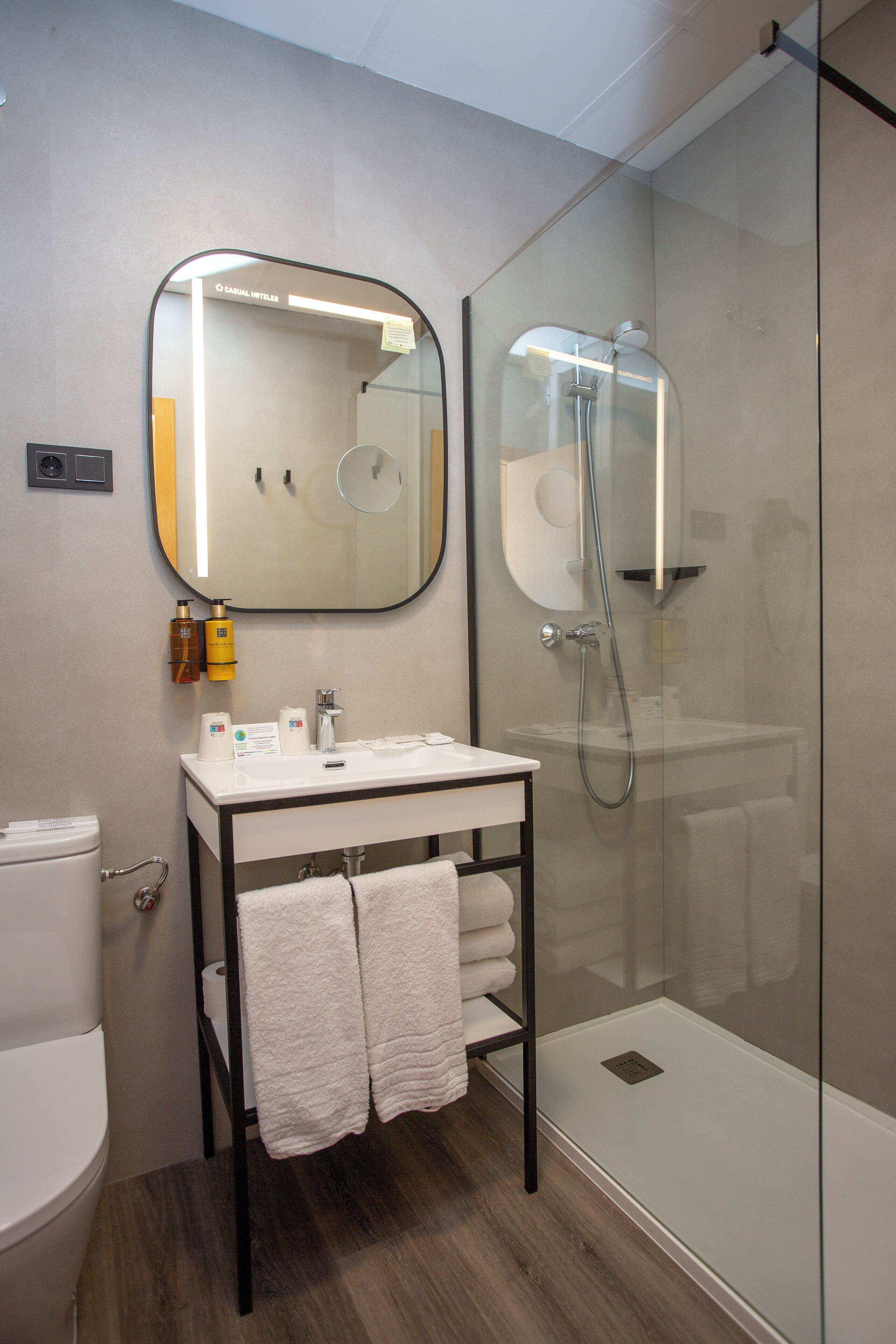 A modern bathroom with a glass-enclosed shower, a white sink, and a mirror above it.