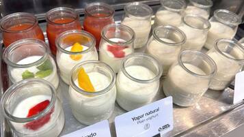 Una presentación de varios sabores de yogur en pequeños frascos de vidrio, algunos con frutas por encima.