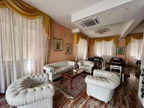 Una sala de estar con un sofá modular, dos sillones, una mesa de centro y un comedor con una mesa y sillas.