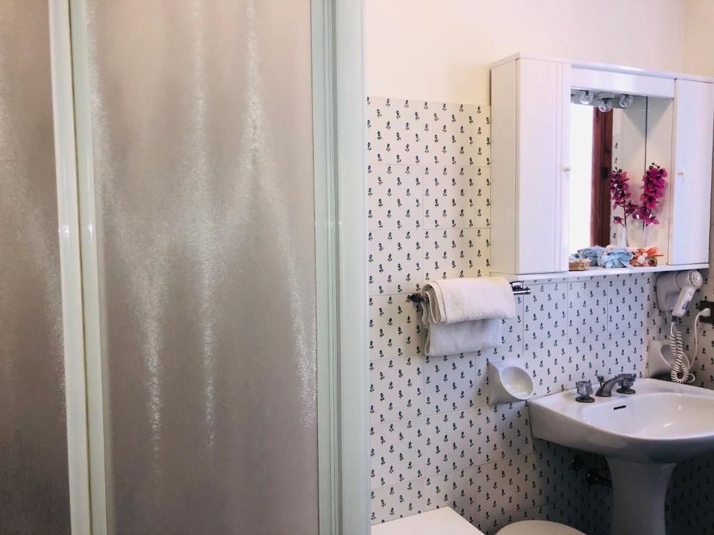 Un baño con ducha, lavamanos y espejo.