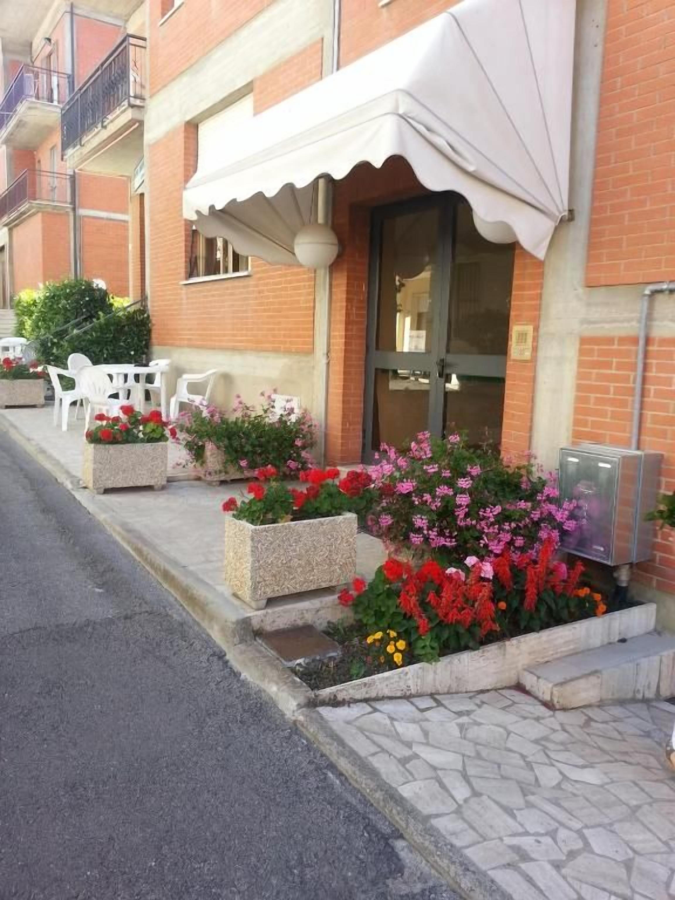 Un bâtiment doté d’un auvent blanc, de places assises en plein air et de jardinières fleuries.