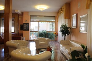 Un salón amplio con sofás de cuero, una mesa de centro y un ventanal con vistas a zonas verdes.