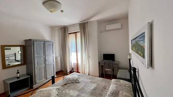 Une chambre à coucher comprenant un lit, une armoire, un bureau avec une chaise, une télévision et un tableau accroché au mur.
