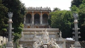 A classical statue garden with a central fountain, surrounded by ornate columns and a backdrop of a classical building. - Rifugio Degli Artisti (Rome)