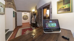 A hotel lobby with a wooden reception desk, a laptop, a telephone, and a framed painting on the wall. - Rifugio Degli Artisti (Rome)
