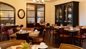 A dining area with multiple tables and chairs, a large cabinet with glass doors, and a chandelier. - Ponte Vineyard Inn (Temecula)