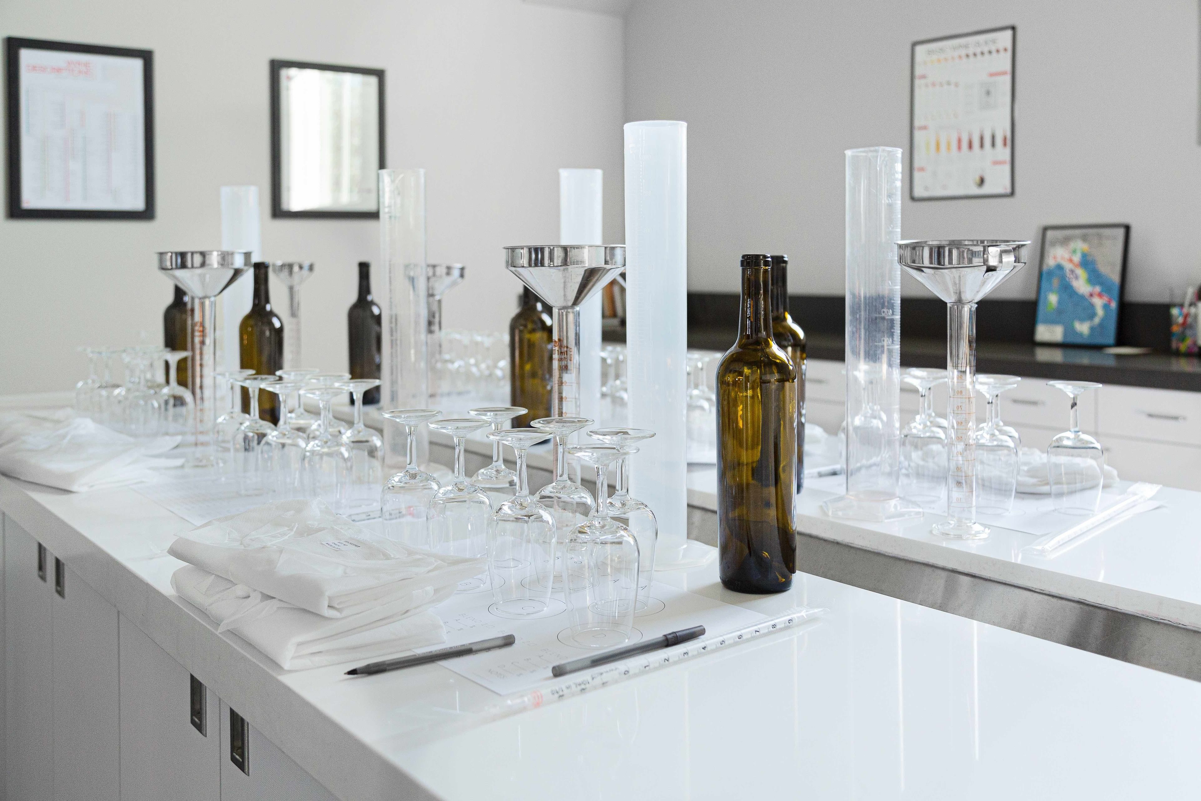 A tasting room with wine glasses, bottles, and tasting sheets on a counter.