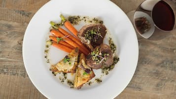 Une assiette de viande, de carottes et un verre de vin rouge.