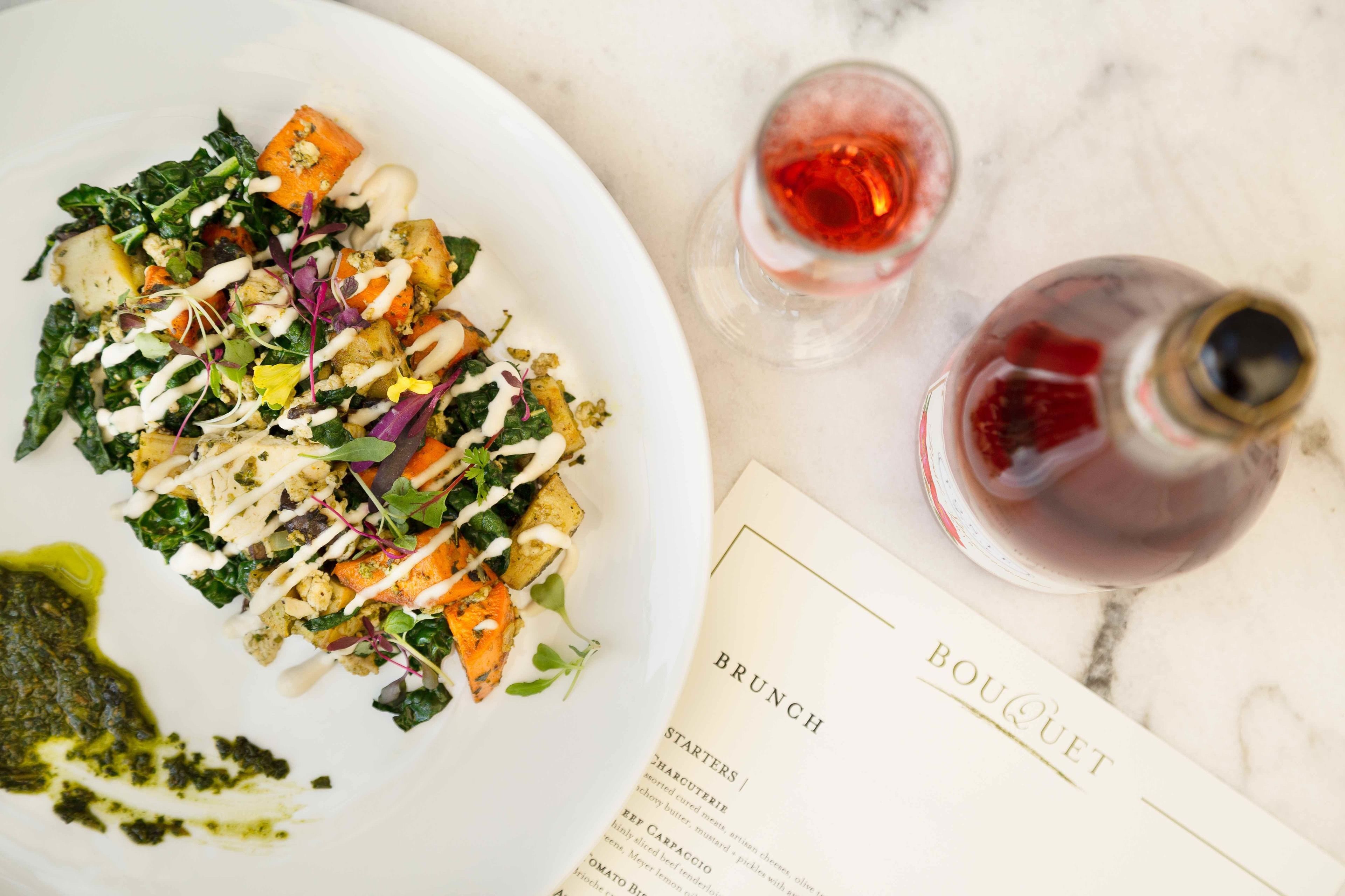 A white plate with a salad, two glasses of red wine, and a menu titled "BRUNCH" and "BOUQUET".