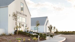A building labeled "TASTING ROOMS" with a staircase leading to the entrance, surrounded by landscaping and a clear sky. - Ponte Vineyard Inn (Temecula)