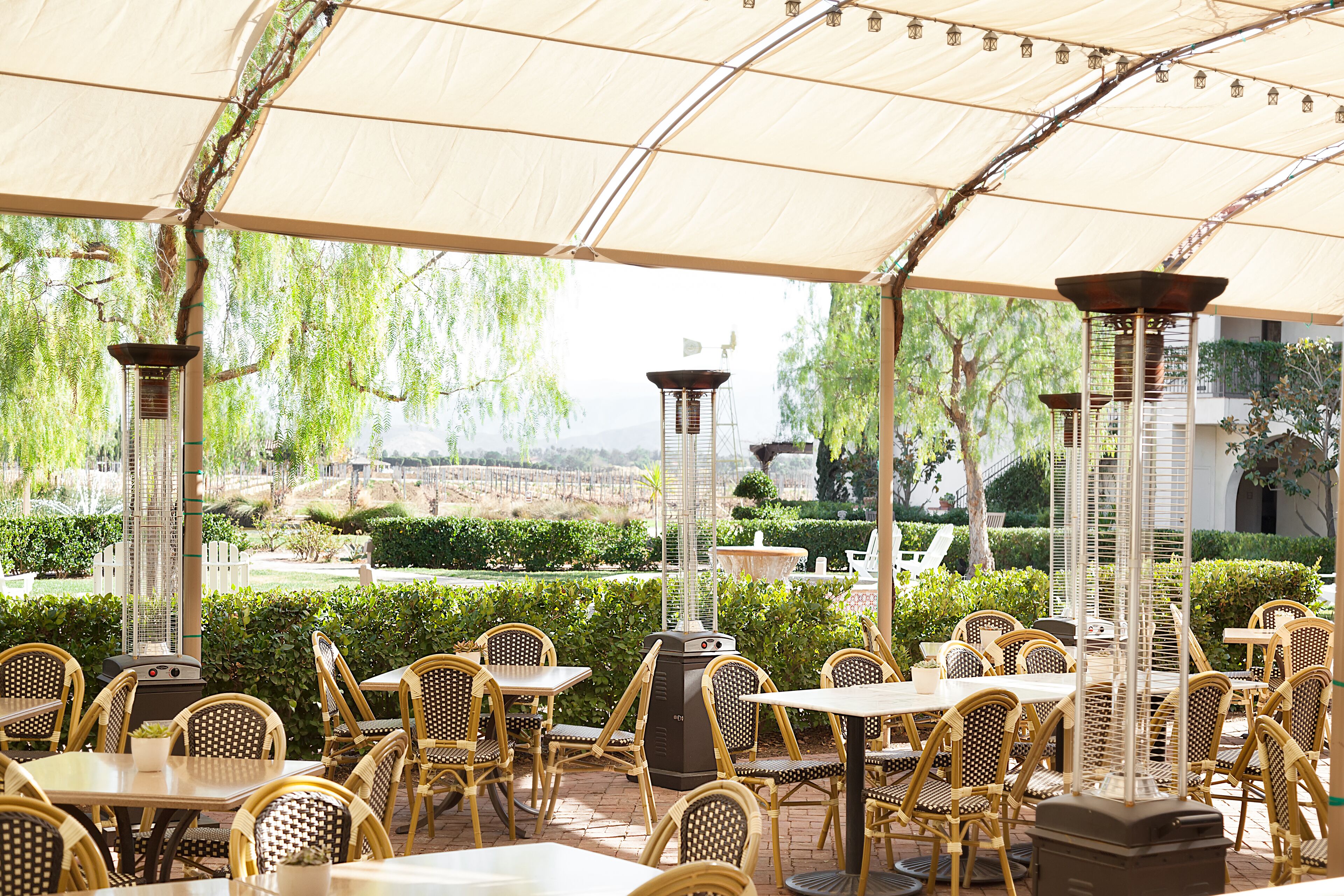 Une terrasse extérieure avec des meubles en osier et une pergola au-dessus.