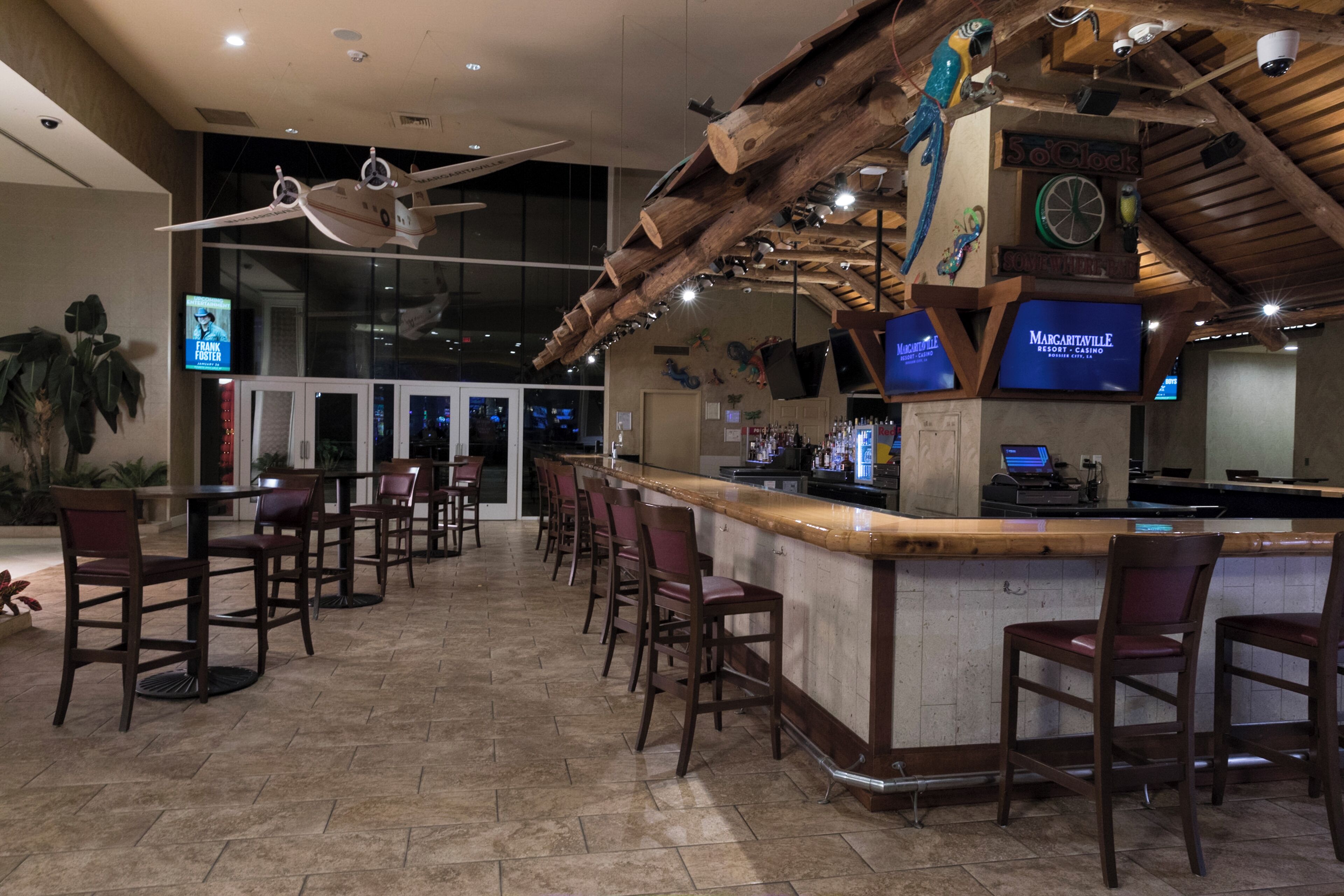 A bar area with wooden ceiling beams, a bar counter, and multiple bar stools.