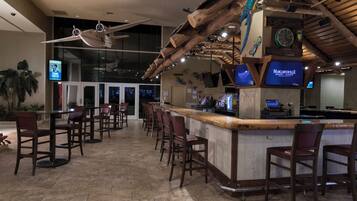 A bar area with wooden ceiling beams, a bar counter, and multiple bar stools.