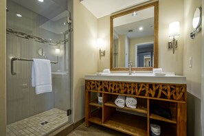 Un baño moderno con ducha de vidrio, tocador de madera y un perchero para toallas.