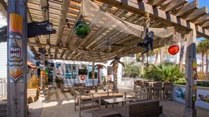 An outdoor seating area with wicker furniture and a wooden pergola. - Margaritaville Resort Casino (Bossier City)