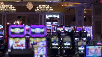 Uma área de cassino com várias máquinas caça-níqueis e uma placa indicando 'High Limit Slots'.