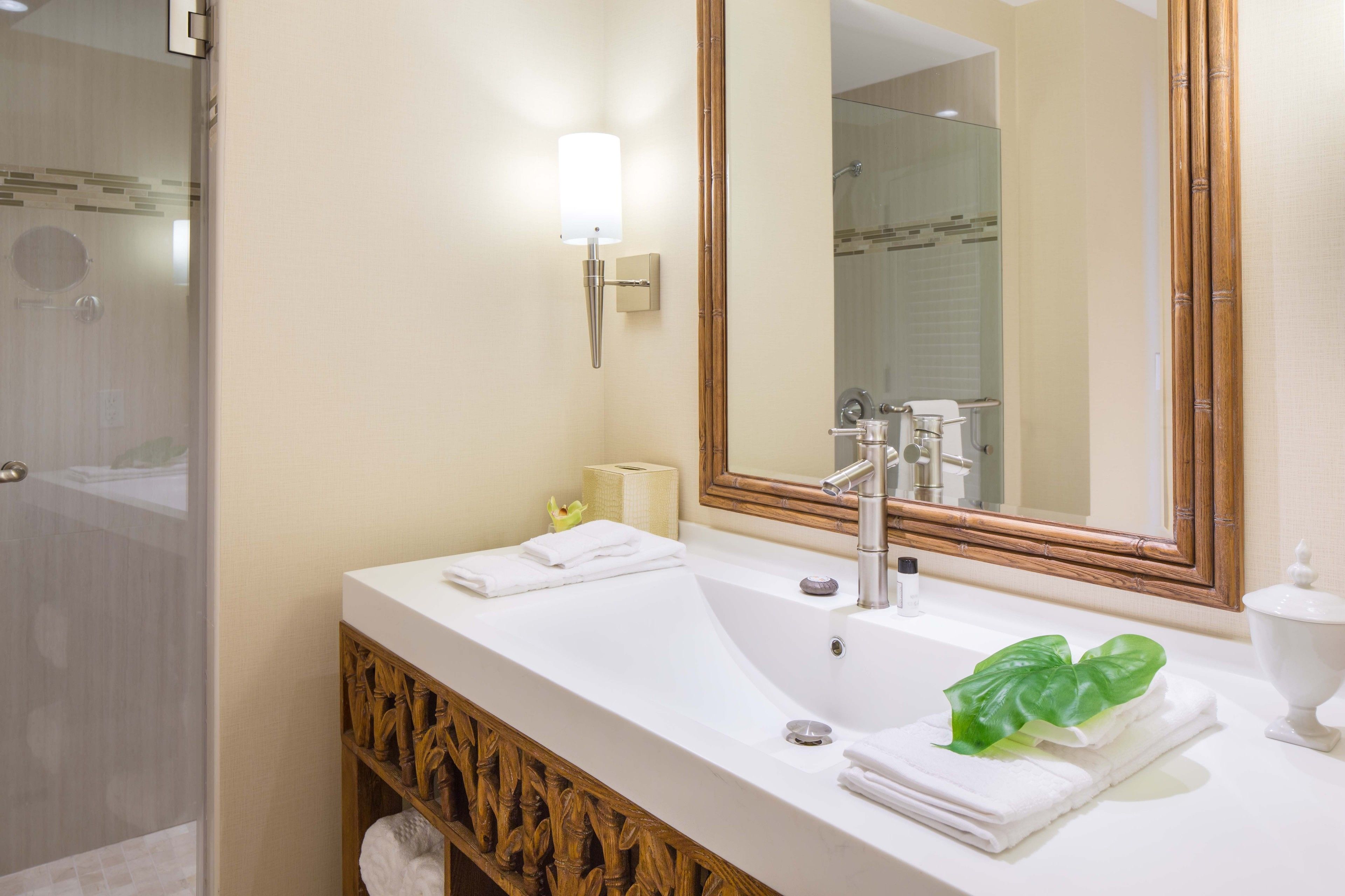 Un baño moderno con un espejo grande, dos lavamanos y una zona de ducha.
