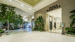 A modern hotel lobby with a polished marble floor, indoor plants, and a sign for the elevator area. - Margaritaville Resort Casino (Bossier City)