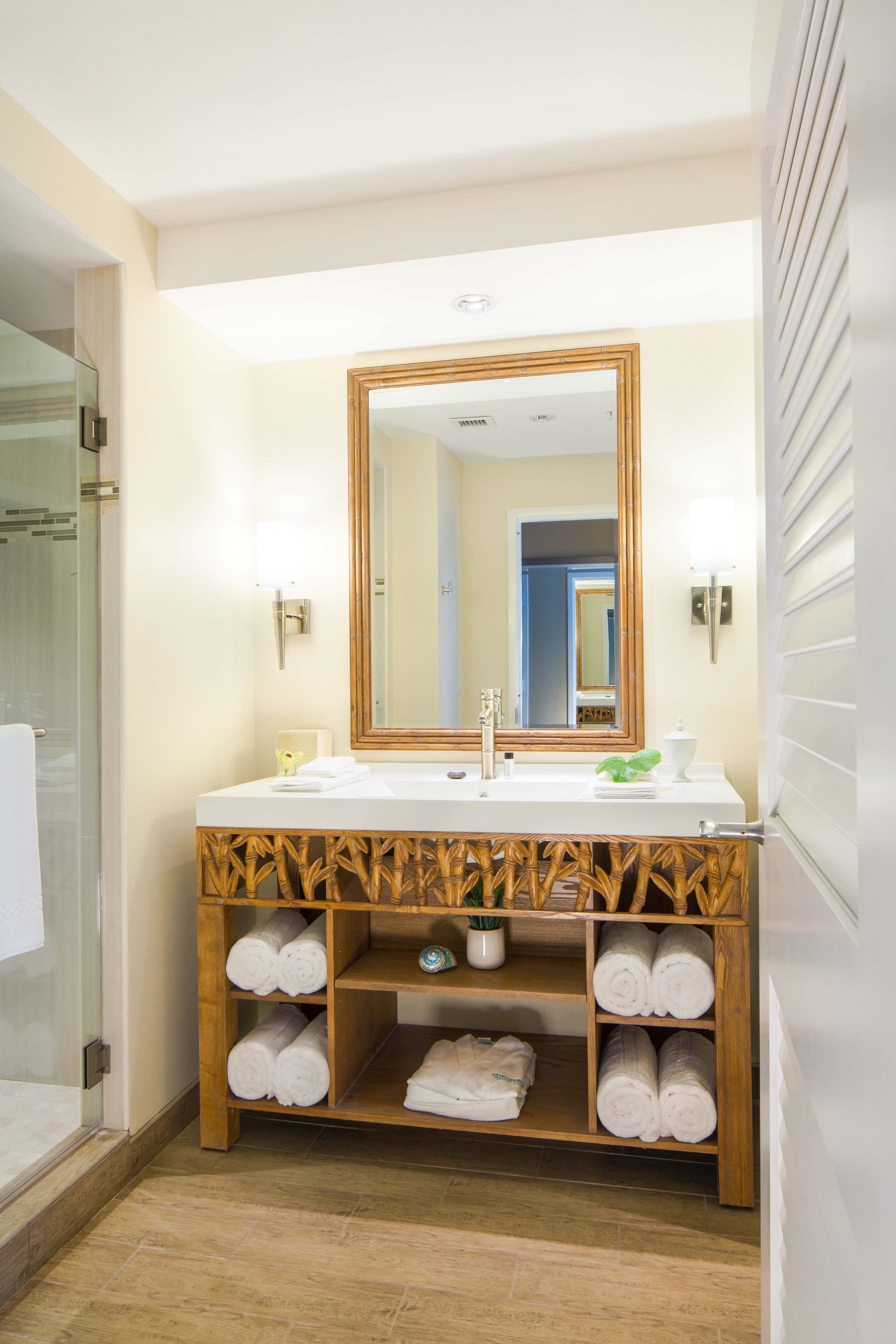 A bathroom with a large mirror, two sinks, and a towel rack with neatly folded towels.