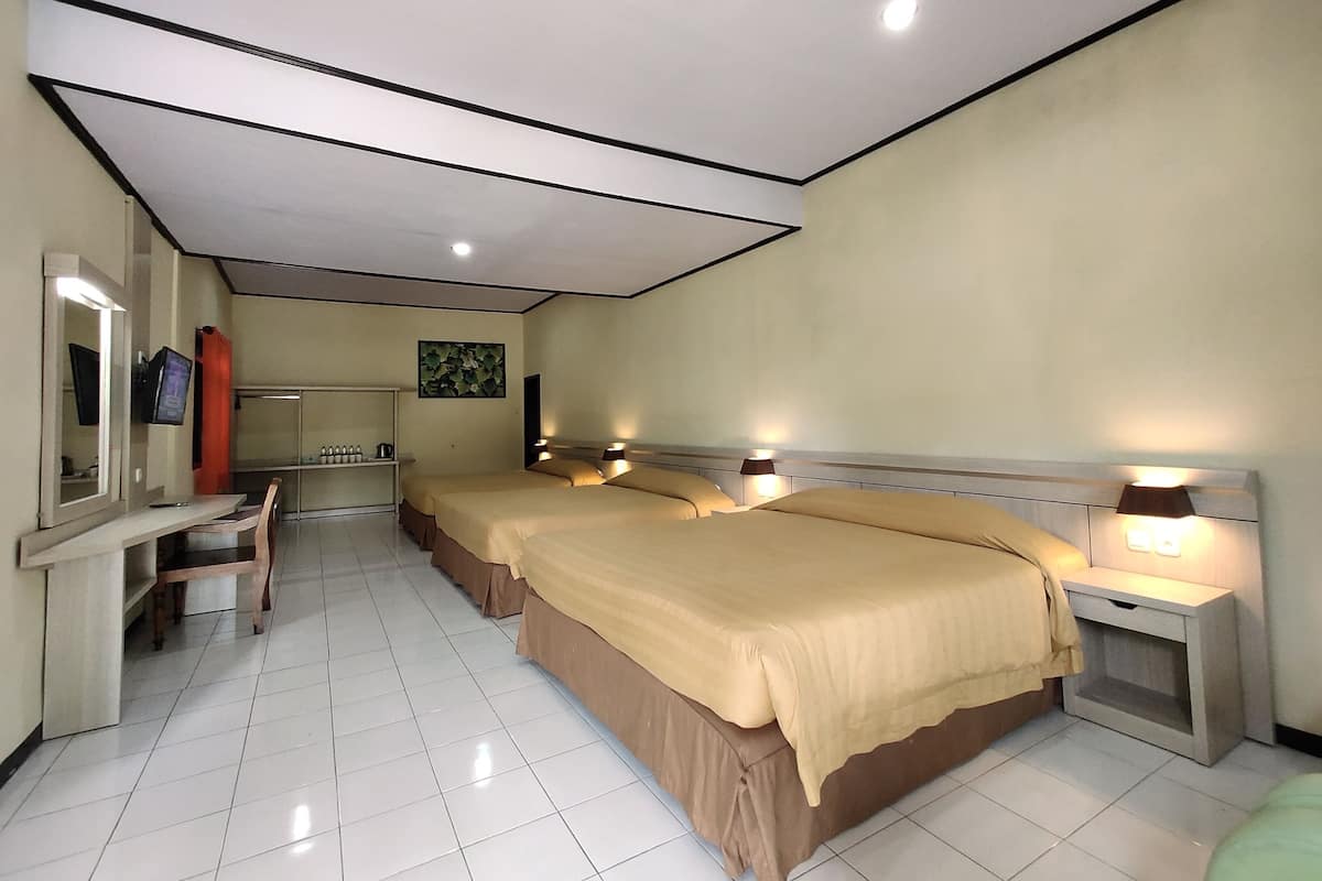 Quarto de hotel com duas camas, uma escrivaninha, uma cadeira, uma televisão e um banheiro.