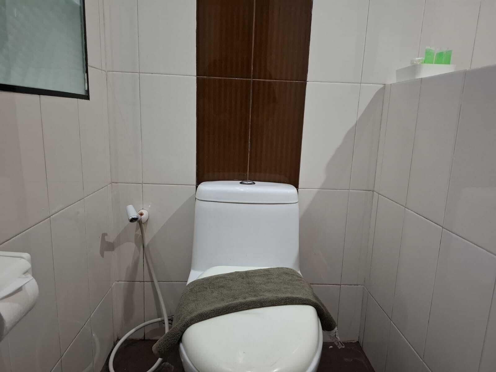 Un bagno piccolo e stretto con un water bianco, un pannello di legno sopra e un lavandino bianco a sinistra.