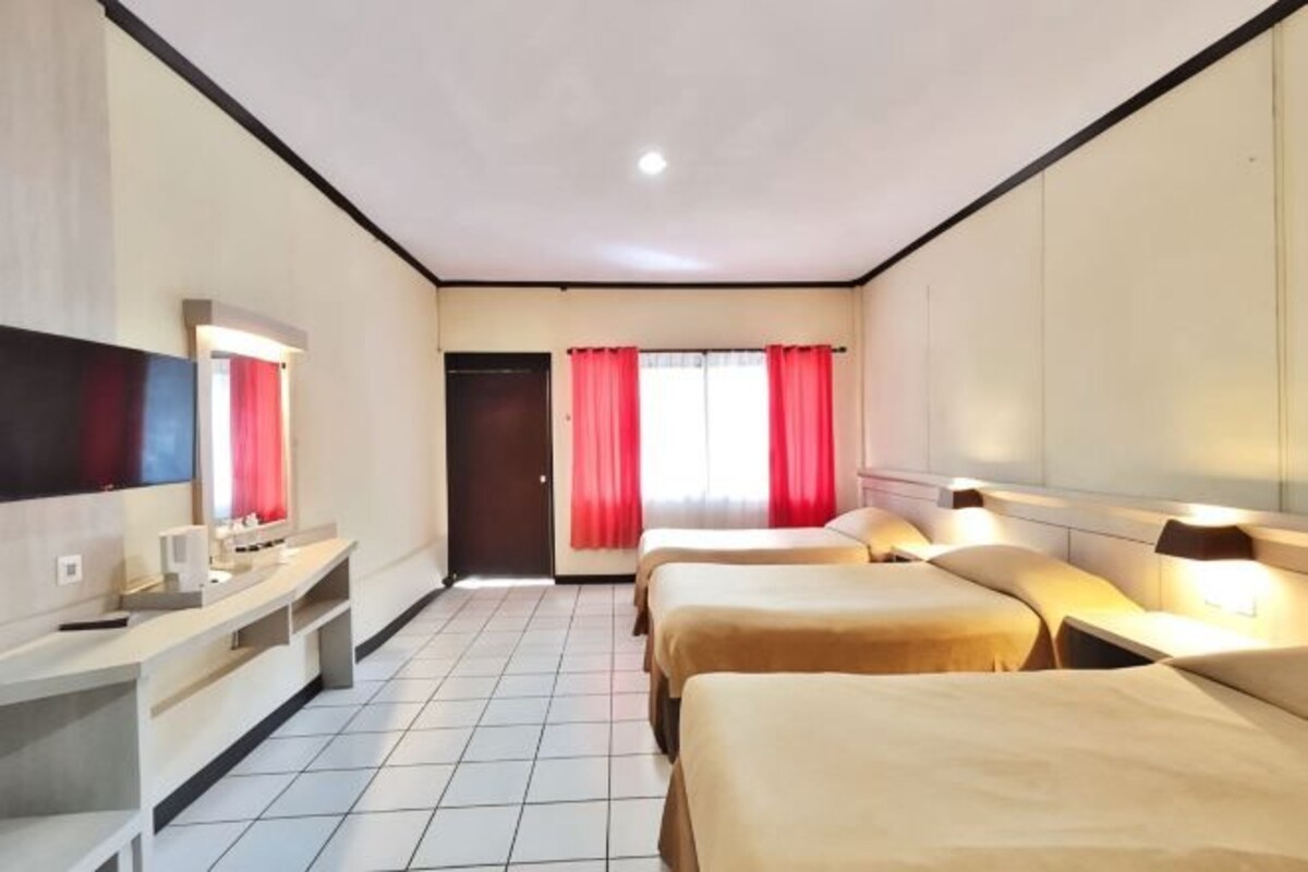 Una habitación de hotel con televisión, escritorio, dos camas y puerta que da al exterior.