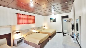 Ein Hotelzimmer mit zwei Betten, einem Schreibtisch, einem Spiegel und einem Fenster mit Vorhang.