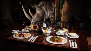 Una mesa de comedor dispuesta con diversos platos, una botella de agua y un adorno con forma de cabeza de animal.