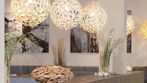Un área de recepción con un mostrador de madera, esferas de madera decorativas suspendidas del techo y obras de arte enmarcadas en las paredes.
