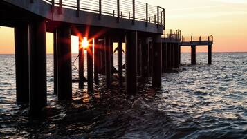 A pier extending into the water with a sunset in the background.