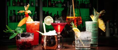A bar with various drinks, including cocktails with garnishes and a copper mug.