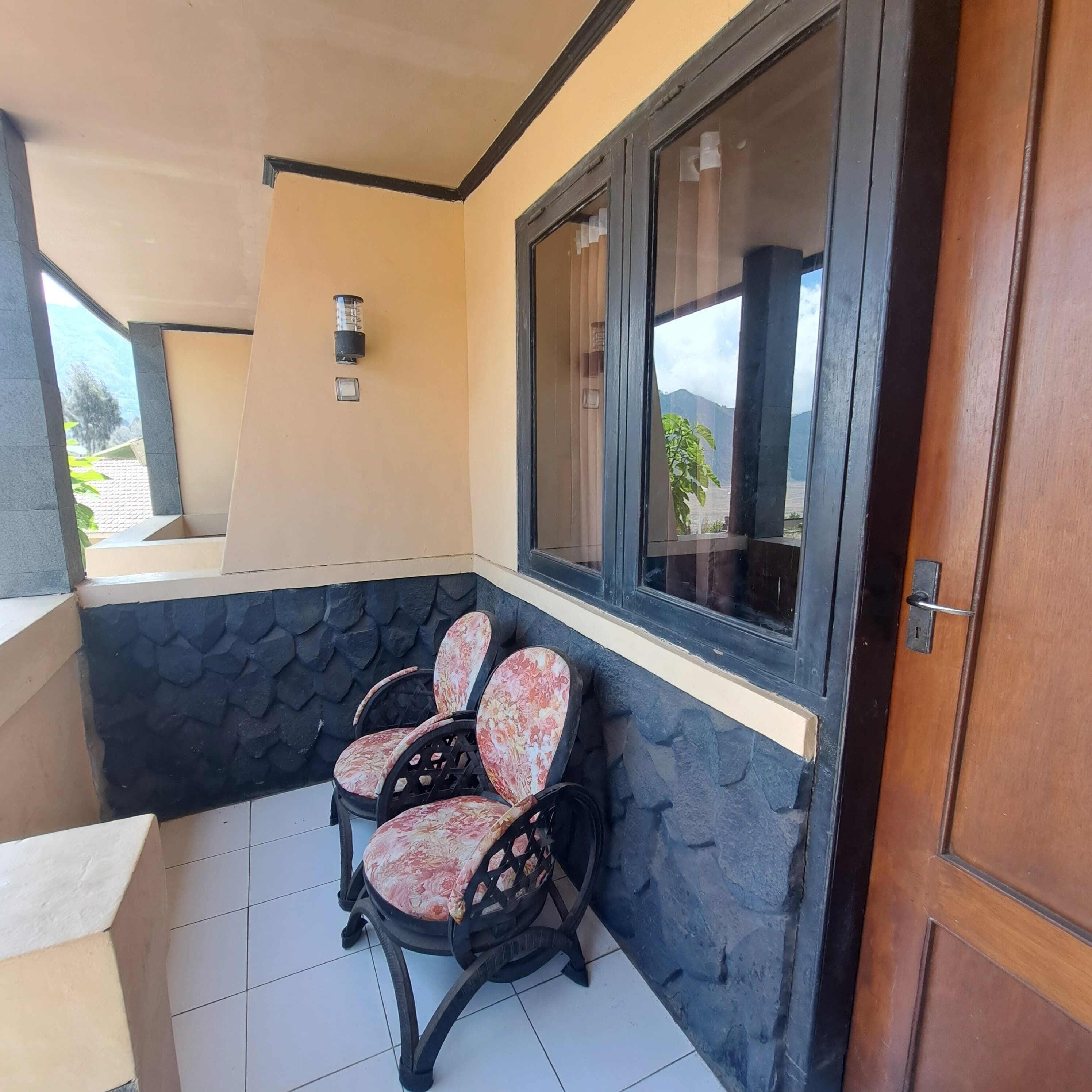 A corner seating area with chairs, a window with a view, and a door.