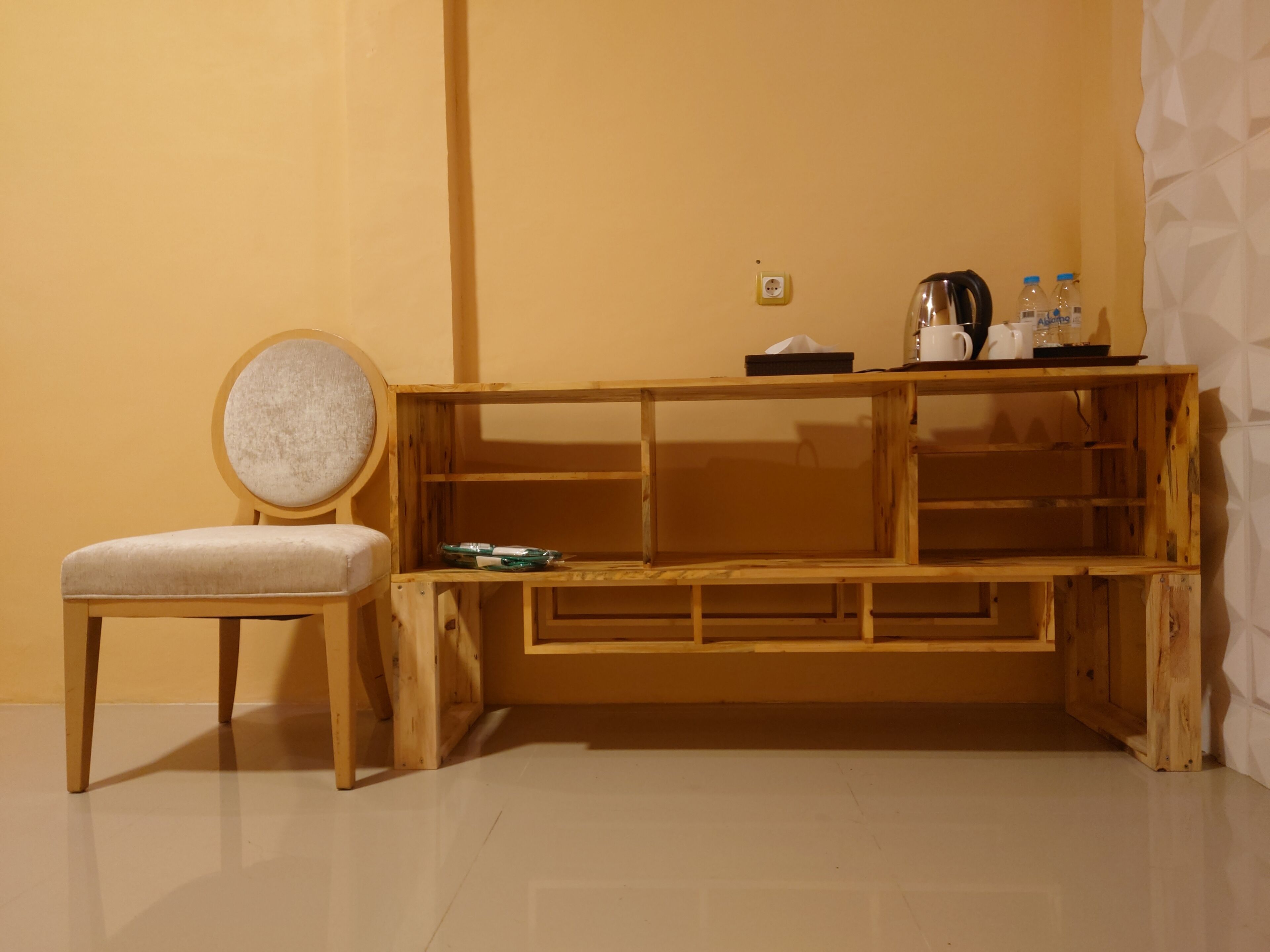 Une pièce d’angle avec un banc en bois, un fauteuil rembourré et une petite table sur laquelle se trouvent une bouilloire et des bouteilles.