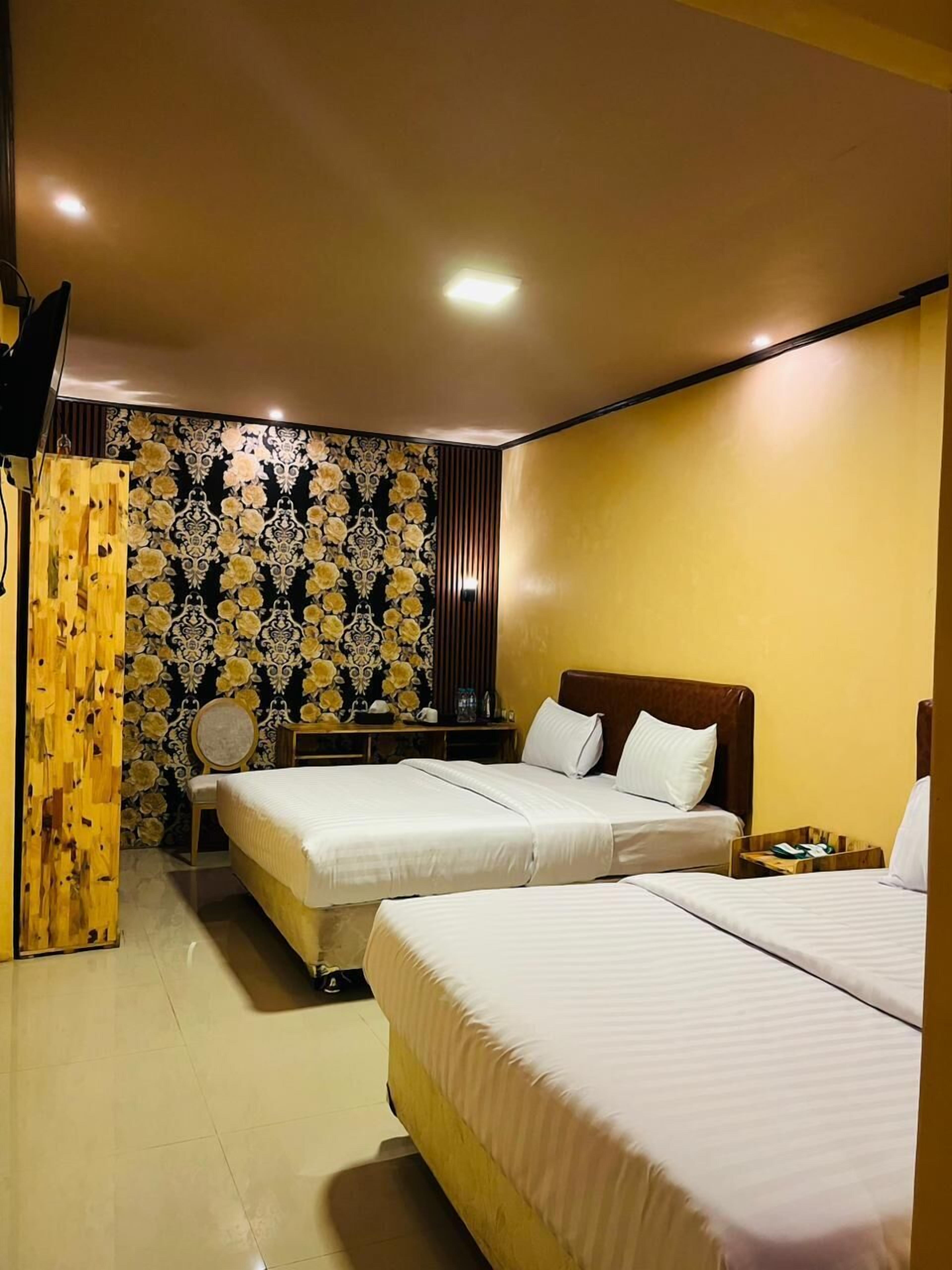 Une chambre d’hôtel avec deux lits, une cloison en bois, un bureau et une chaise.