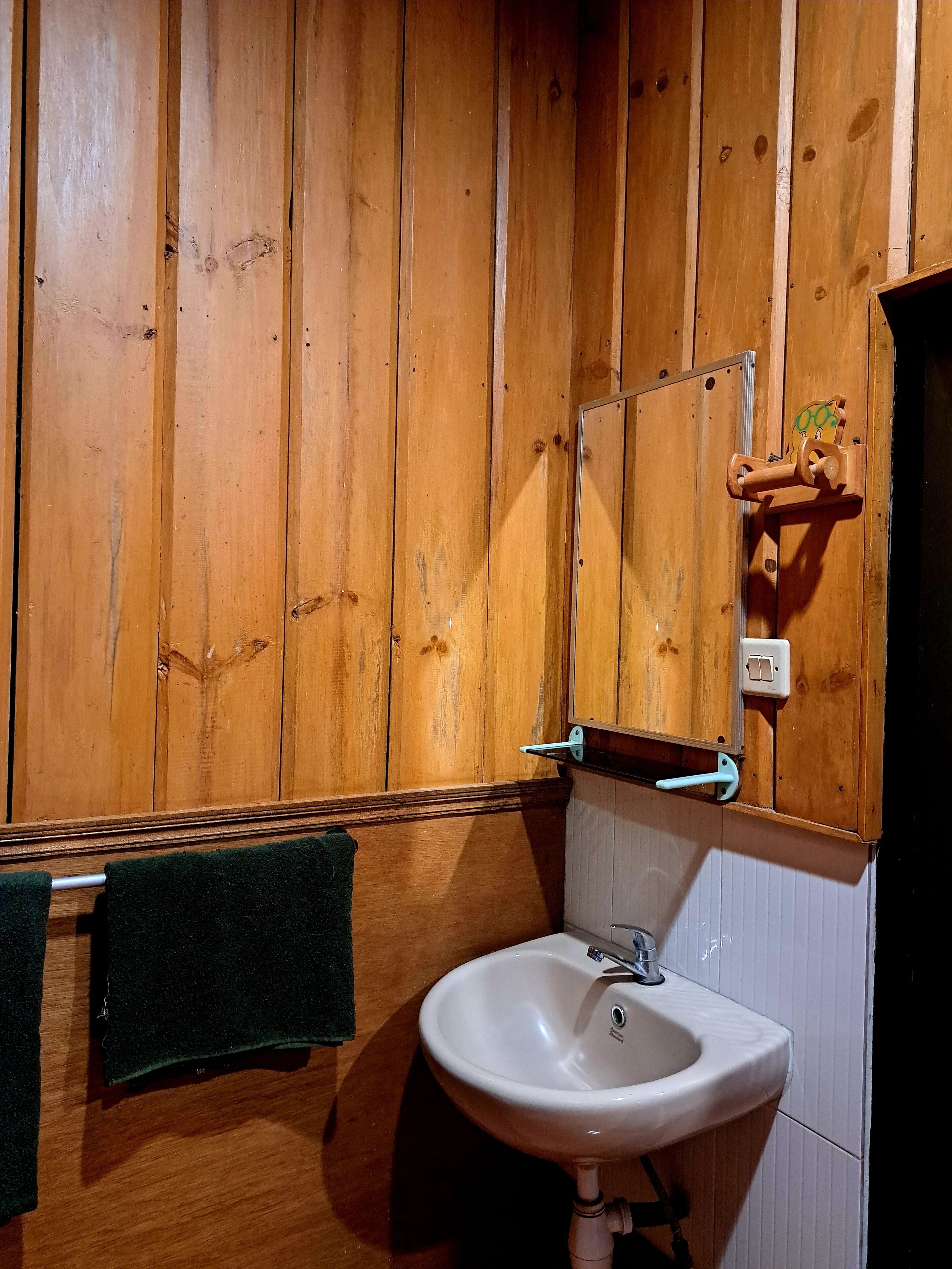 A wooden-paneled bathroom with a white sink, a towel rack, and a mirror.