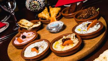A wooden board with various dishes, including dips and flatbreads, arranged on a table.