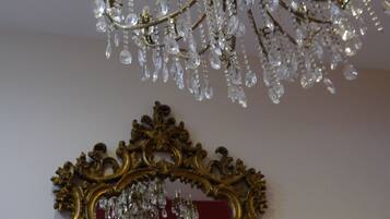 A chandelier with multiple crystal elements and a gold ornate mirror frame.