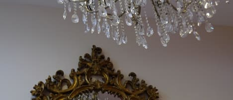 A chandelier with multiple crystal elements and a gold ornate mirror frame.