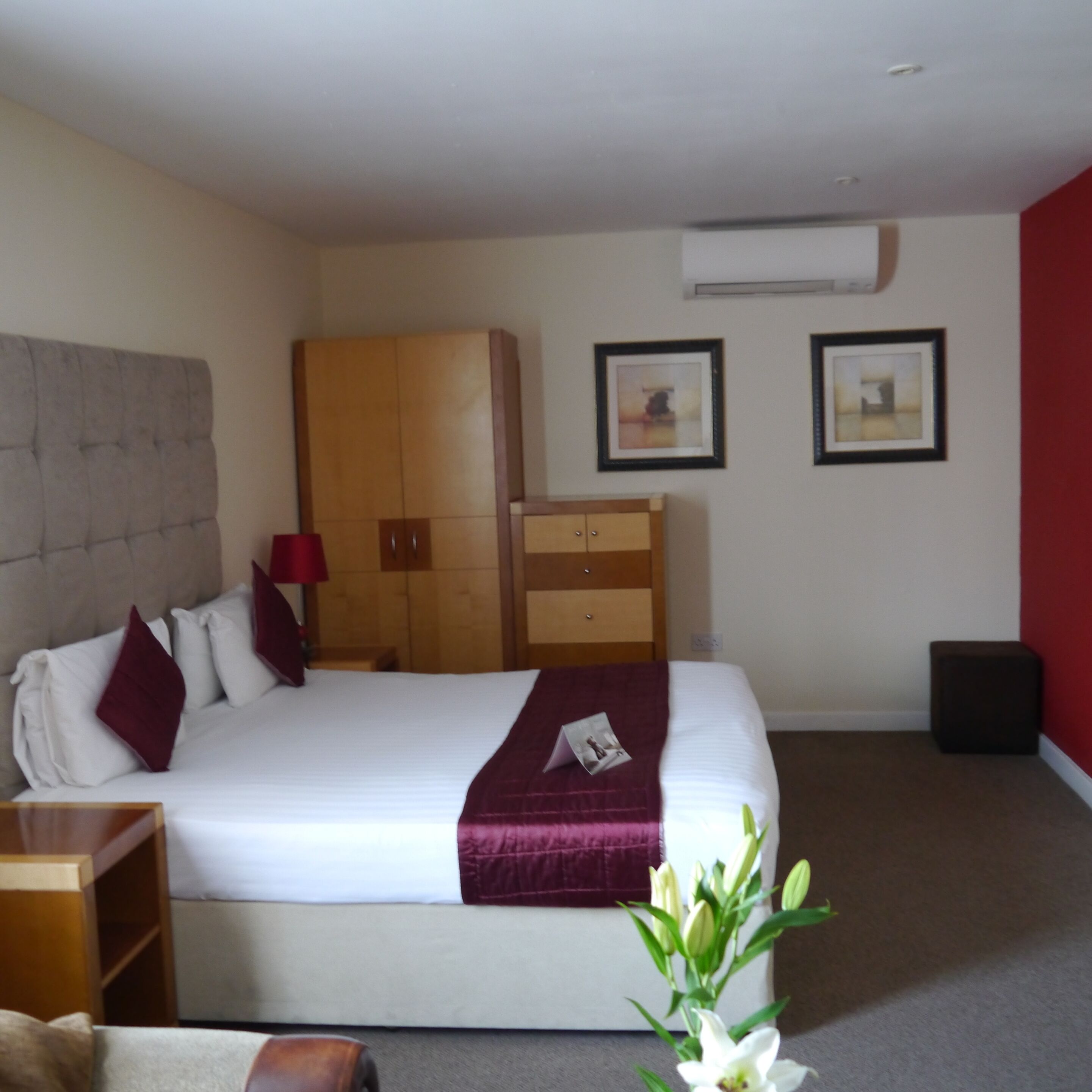 A hotel room with a bed, a wardrobe, a nightstand, and a small table.