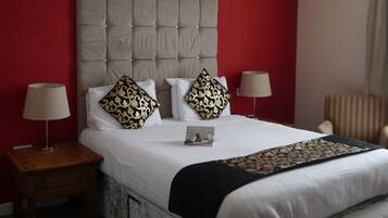 A hotel room with a large bed, two bedside tables, and a chair.